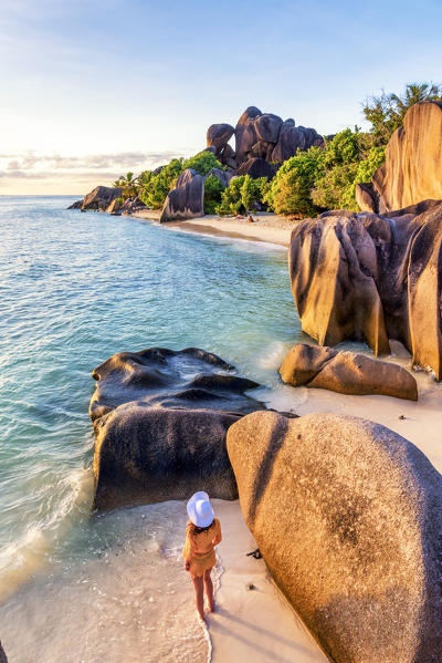 A young woman admires the sunset at Anse Source d'Argent, La Digue, Seychelles, Africa (MR)