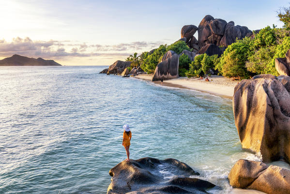 A young woman admires the sunset at Anse Source d'Argent, La Digue, Seychelles, Africa (MR)