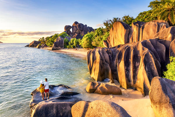 A young couple admires the sunset at Anse Source d'Argent, La Digue, Seychelles, Africa (MR)