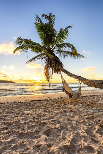A woman relaxing on a hammock at sunrise. La Digue, Seychelles, Africa