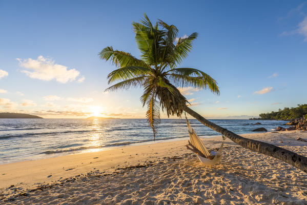 A woman relaxing on a hammock at sunrise. La Digue, Seychelles, Africa