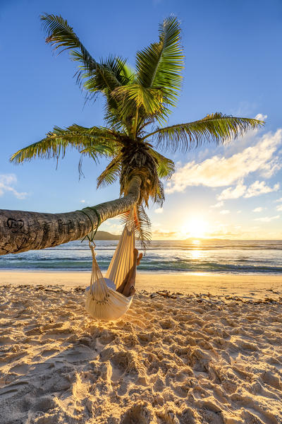 A woman relaxing on a hammock at sunrise. La Digue, Seychelles, Africa (MR)