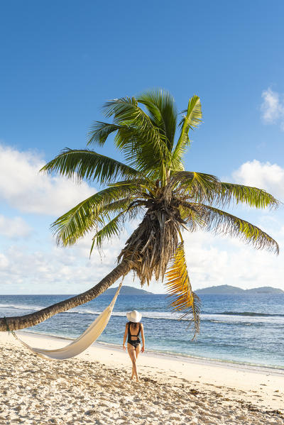 A beautiful woman walking along the beach. La Digue, Seychelles, Africa (MR)