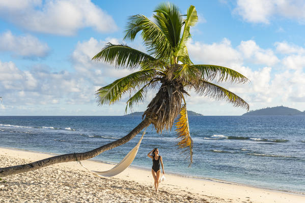 A beautiful woman walking along the beach. La Digue, Seychelles, Africa (MR)