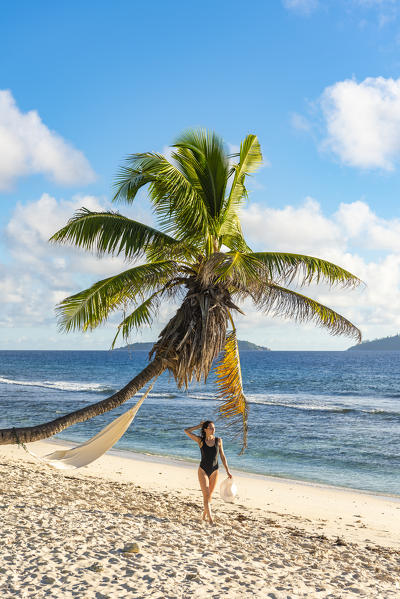 A beautiful woman walking along the beach. La Digue, Seychelles, Africa (MR)