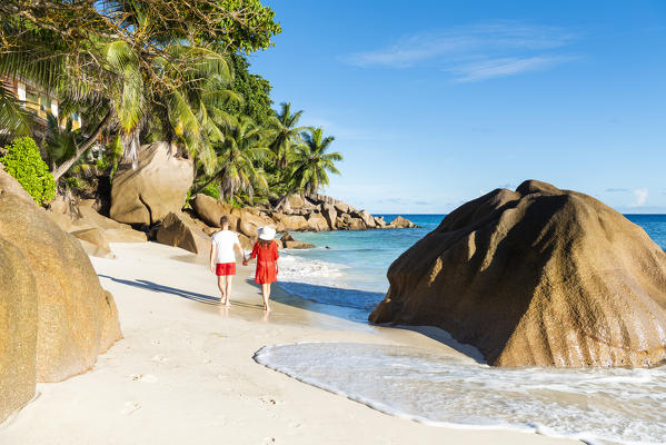 A couple walking along Anse Patates beach. La Digue, Seychelles, Africa