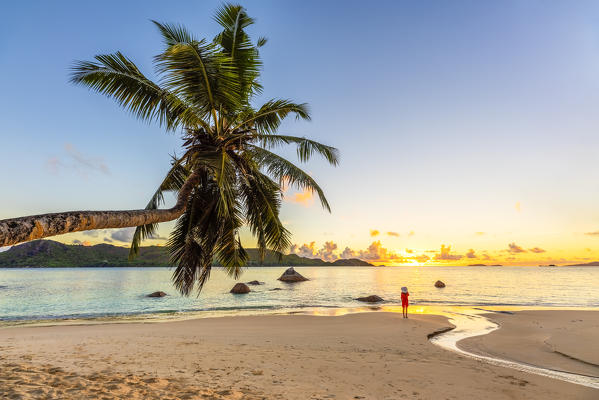 A tourist admiring the sunrise on Anse Boudin, Praslin island, Seychelles, Africa (MR)