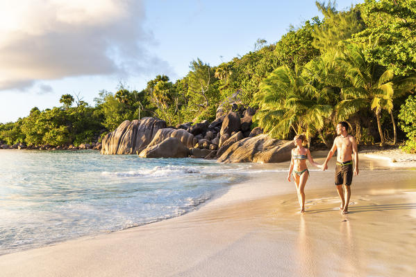 A beautiful couple walking along Anse Lazio beach at sunset. Praslin island, Seychelles, Africa