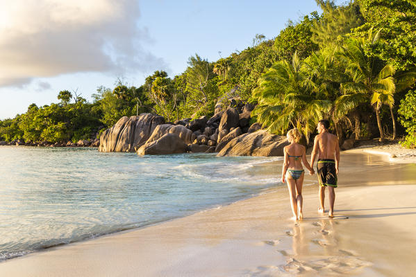 A beautiful couple walking along Anse Lazio beach at sunset. Praslin island, Seychelles, Africa
