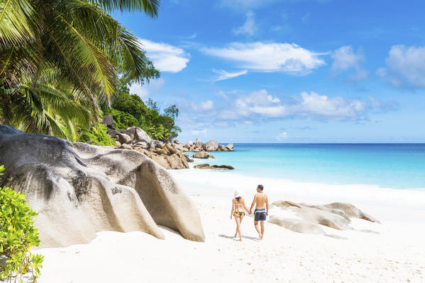 A couple walking along Anse Georgette beach. Praslin, Seychelles, Africa