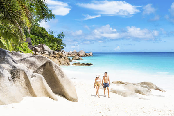 A couple walking along Anse Georgette beach. Praslin, Seychelles, Africa