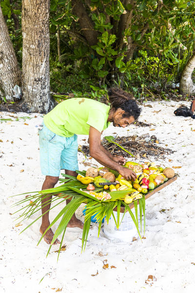 Local man preparing a plate of fresh tropical fruits. Praslin island, Seychelles, Africa