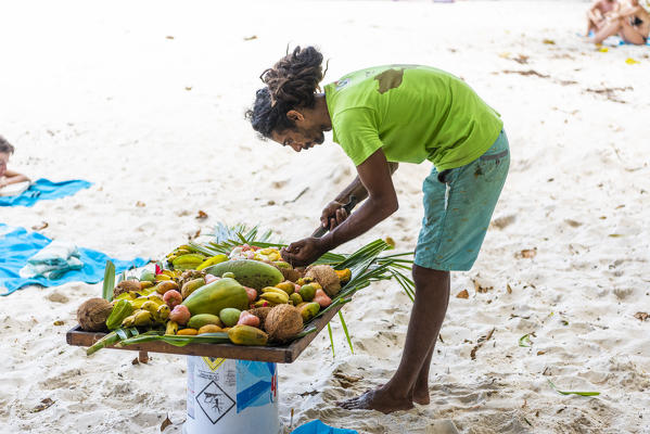 Local man preparing a plate of fresh tropical fruits. Praslin island, Seychelles, Africa