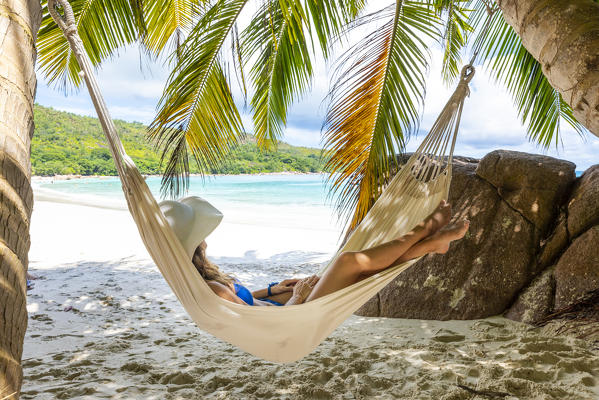 A young woman relaxing on a hammock. Anse Lazio beach, Praslin island, Seychelles, Africa (MR)