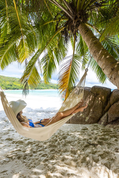 A young woman relaxing on a hammock. Anse Lazio beach, Praslin island, Seychelles, Africa (MR)