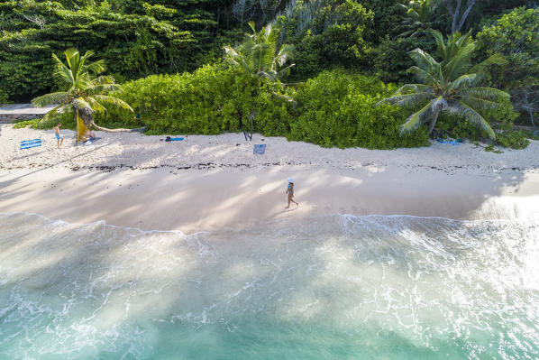 A woman strolling along Anse Fourmis beach. La Digue, Seychelles, Africa