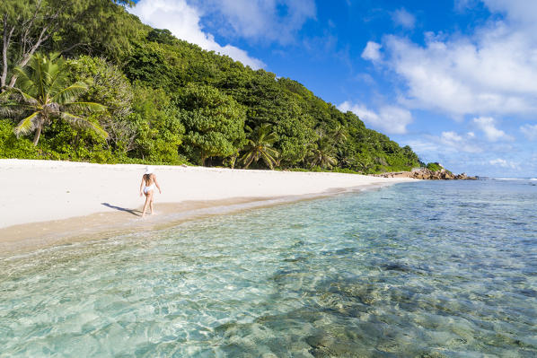 A woman strolling along Anse Fourmis beach. La Digue, Seychelles, Africa