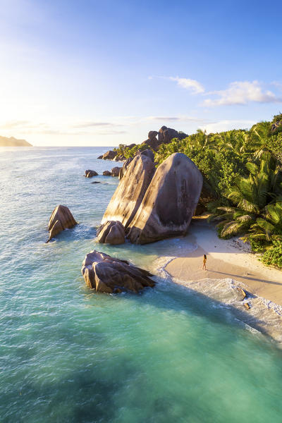 Aerial view of Anse Source d'Argent beach at sunset. A woman enjoys the view. La Digue island, Seychelles, Africa