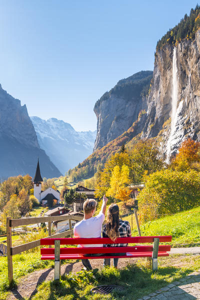 A young couple admires Lauterbrunnen village. Lauterbrunnen, Canton of Bern, Switzerland, Europe