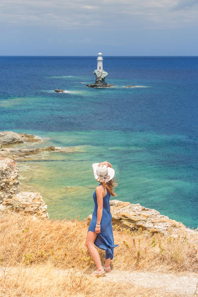 Young woman admiring the enchanting offshore Tourlitis lighthouse, Andros, Cyclades Archipelago, Greece, Europe (MR)