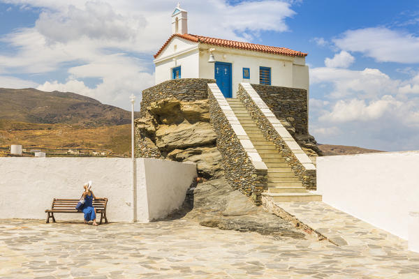 Tourist in a blue dress relaxing on a bech near St, Thalassini Church, Andros, Cyclades archipelago, Greece, Europe