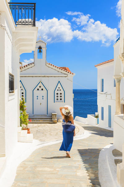 Young woman walking on the street that leads to the Church of St. Barbara, Andros, Cyclades archipelago, Greece, Europe (MR)