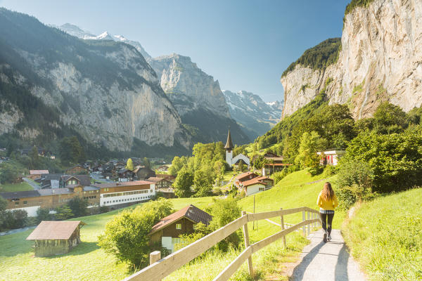 A young woman walking on a street in the village of Lauterbrunnen,Interlaken-Oberhasli administrative district, canton of Bern,Bernese Oberland, Switzerland.