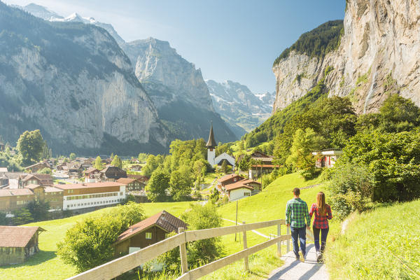 Couple of tourists walking on a street in the village of Lauterbrunnen,Interlaken-Oberhasli administrative district, canton of Bern,Bernese Oberland, Switzerland.