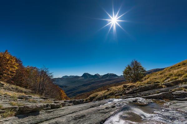 Small waterfall in autumn with Gran Sasso peaks in the background, Laga Mountais, L'Aquila province, Abruzzo, Italy, Europe
