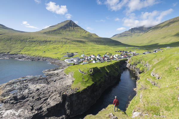 Hiker admiring little village of Gjogv, Eysturoy island, Faroe Islands, Denmark, Europe