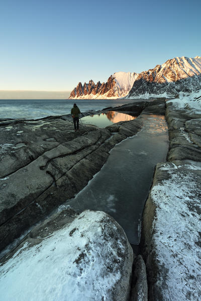 a photographer captures the Devil's teeth Mountain, reflections at sunset in a puddle along the Ersfjorden, Senja, Northern Norway, Europe.