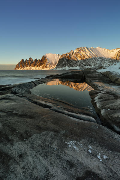the Devil's teeth Mountain, reflections at sunset in a puddle along the Ersfjorden, Senja, Northern Norway, Europe.