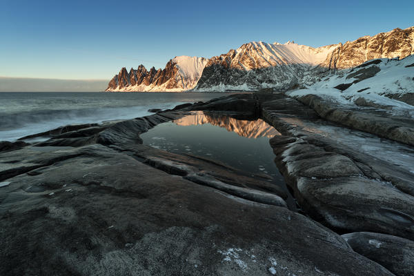 the Devil's teeth Mountain, reflections at sunset in a puddle along the Ersfjorden, Senja, Northern Norway, Europe.