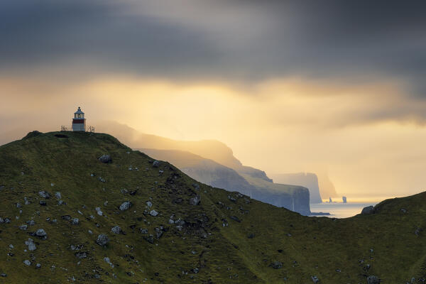 a magical light envelope the Risin og Kellingin during an autumn sunset, with the Kallur lighthouse in foreground, Eysturoy, Faroe Islands, Denmark, Scandinavia