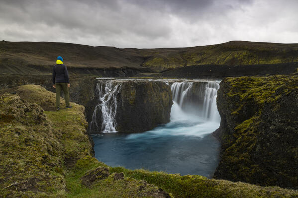 a hiker admires the Sigoldufoss waterfall on a summer day, Iceland, Europe
