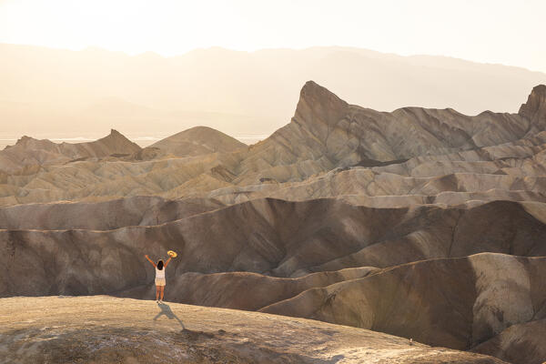a woman admire the beautiful view at Zabriskie Point during a summer sunset, Death Valley National Park, California, United States of America