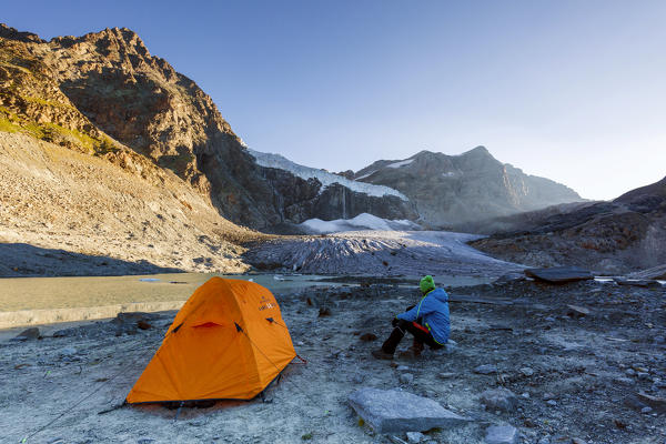 Hiker out of tent looks at Fellaria Glacier, Malenco Valley, Sondrio Province, Valtellina, Lombardy, Italy Europe