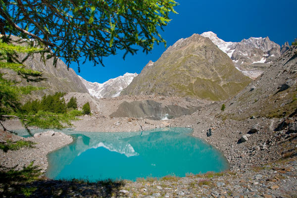 An alpine lake, under a glacier, with peaks in the background. Miage lake, Veny valley, Aosta Valley