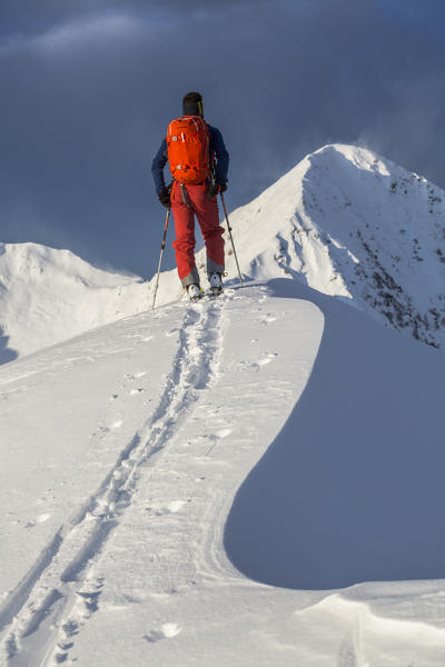 Ski mountaineer on snowy peak of Cima Rosetta, Gerola Valley, Sondrio province, Valtellina, Lombardy, Italy