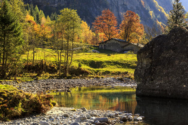Autumn colors mirrored in lake of Bidet della Contessa, Val di Mello, Val Masino, Sondrio province, Valtellina, Lombardy, Italy