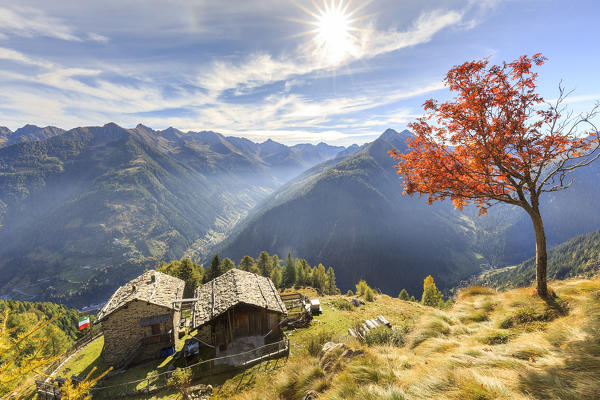 Sunburst on the autumnal landscape at Alpe Paglia, Tartano Valley, Sondrio province, Valtellina, Lombardy, Italy