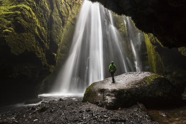 Man into a cave in front of a waterfall, Gljufrafoss, Skógar, Iceland, Northern Europe  (MR)