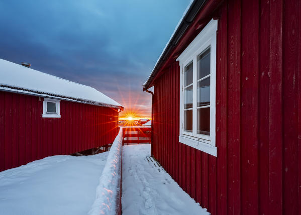 Sunburst at sunrise through rorbuer, A I Lofoten, Moskenes, Moskenesoya, Nordland, Lofoten, Norway, Northern Europe