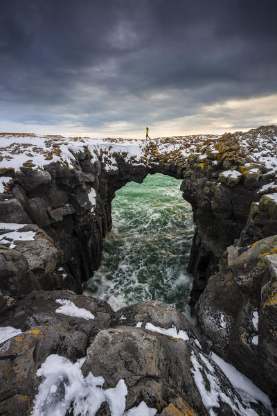 A man walks along Stone bridge, Arnarstapi, Snæfellsnes peninsula, Iceland, Northern Europe