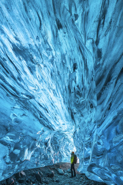 Man observes an ice cave of Breidamerkurjokull, Austurland, Iceland, Northern Europe