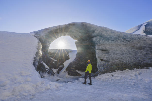 Man under an arch of ice of Breidamerkurjokull, Austurland, Iceland, Northern Europe