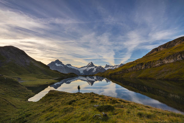 A man stands in front of Bachalpsee and mountains during sunrise, Jungfrau region, Canton Berna, Oberland, Switzerland, Western Europe (MR)