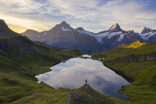 Aerial view of a man stands in front of Bachalpsee and mountains during sunrise, Jungfrau region, Canton Berna, Oberland, Switzerland, Western Europe