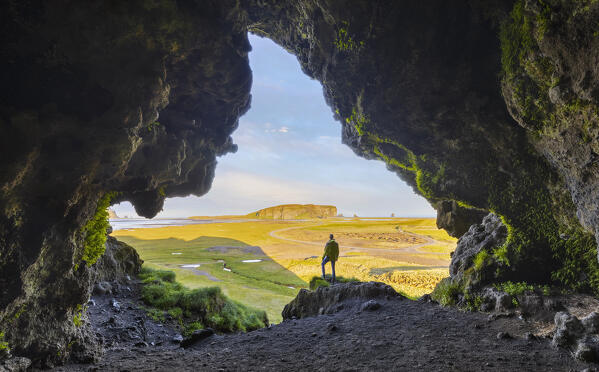 A man observes Dyrholaey cliff from a cave during summer, Vik I Myrdal, southern Iceland, Iceland, Northern Europe (MR)