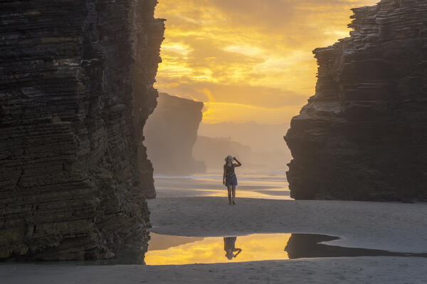 Woman walks at Playa de Las Catedrales at sunset, Ribadeo, Galicia, Spain, Iberian Peninsula, Western Europe (MR)